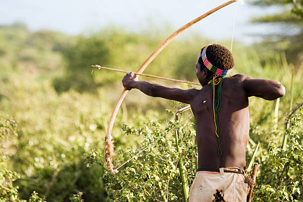 Lake Eyasi, Tanzania - February 18, 2013: Hazabe bushman with bow and arrow during hunting in the bush. Hazabe tribe threatened by extinction.